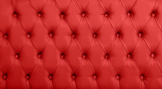 Feche acima da textura do fundo de couro genuíno capitone vermelho escarlate, estofamento de móveis de tufos macios estilo Chesterfield retrô com padrão de diamante profundo e botões