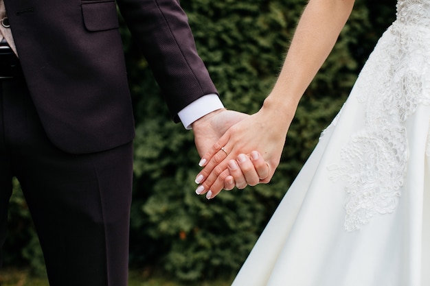 Feche acima da vista do noivo e da noiva de mãos dadas. Casal jovem romântico feliz comemorando seu casamento