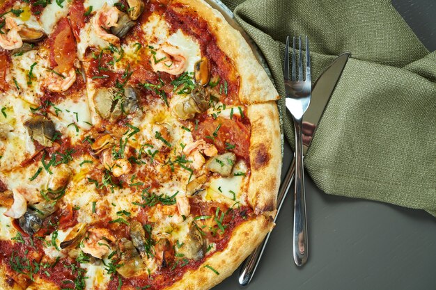 Feche acima da vista na pizza apetitosa com molho vermelho, mexilhões e camarão na mesa de madeira em um restaurante. Cozinha italiana. Vista superior, espaço de cópia