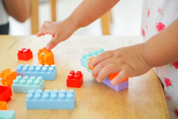 Feche acima das mãos da criança que jogam com os brinquedos coloridos do conector na tabela. Brinquedos educativos para criança pré-escolar e jardim de infância.