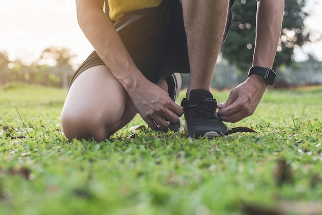 Feche acima das mãos masculinas que amarram o laço em tênis de corrida.