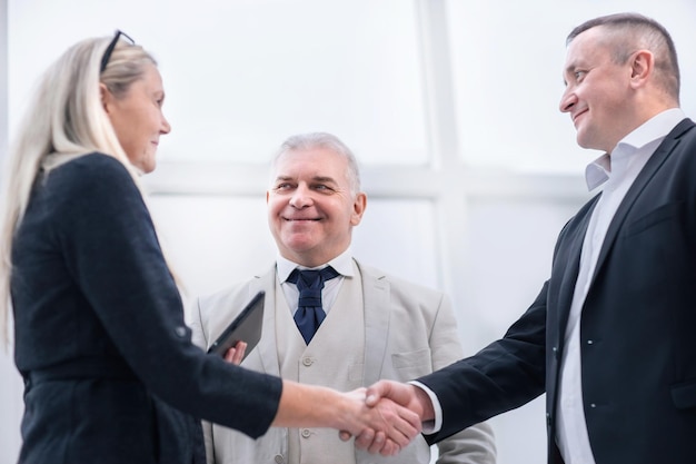 Feche acima de executivos sorrindo apertando as mãos