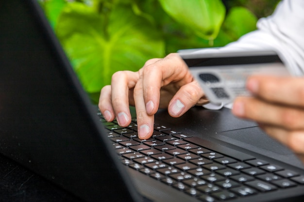 Feche acima de um homem que compra em linha Usando o portátil com cartão de crédito. Hand Holding Credit Card Over Laptop Online Shopping Concept