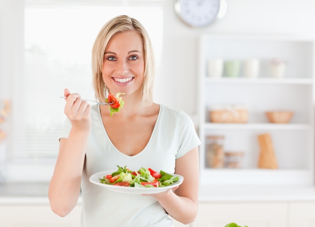 Feche acima de uma linda mulher comendo salada