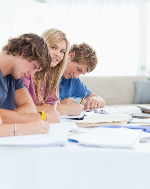 Feche acima de uma menina sorridente olhando a câmera com ela estudando amigos