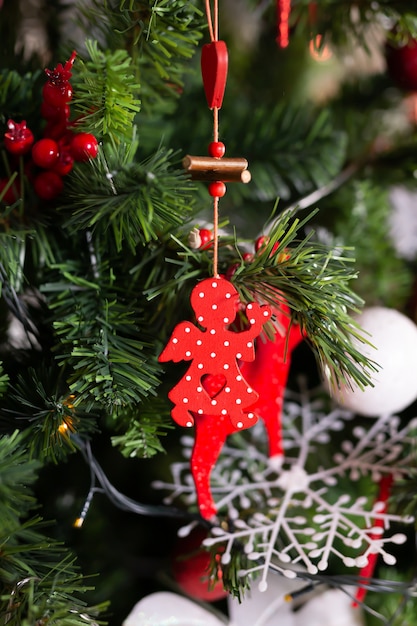 Feche acima do brinquedo vermelho do anjo do natal na árvore de natal. feliz ano novo e conceito de natal. decoração.