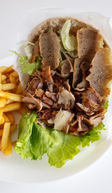 Feche acima do doner kebab com batatas fritas isoladas no fundo branco