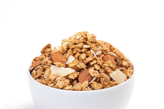 Feche acima do Granola na bacia branca isolada no fundo branco.