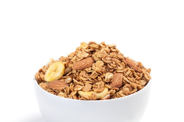 Feche acima do Granola na bacia branca isolada no fundo branco.