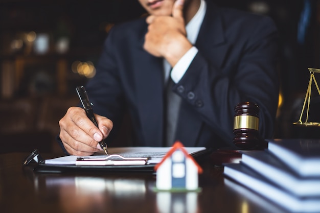 Feche acima do homem de negócios do advogado que escreve ou que lê o original do contrato no local de trabalho do escritório para o conceito do advogado do consultante.