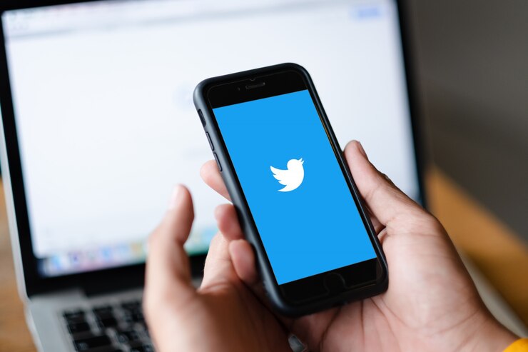 Foto feche acima do homem que guarda smartphone disponível começam a usar a aplicação do twitter.