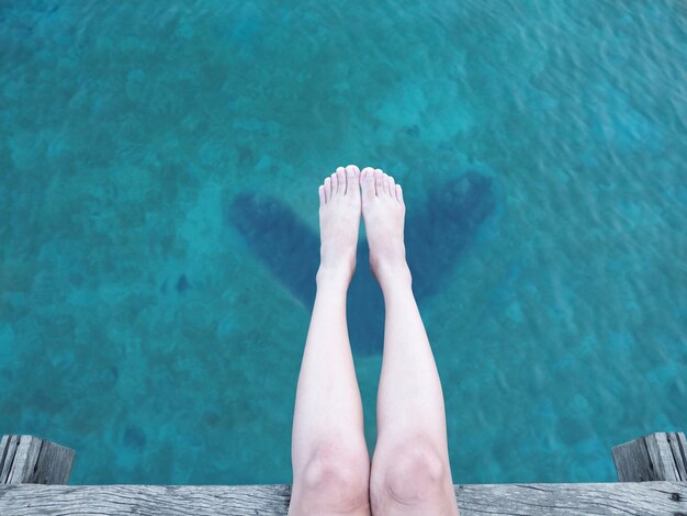 Feche acima do pé e do pé da mulher sobre o mar azul.