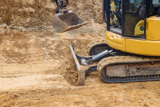 Feche acima do solo móvel da escavadora para o canteiro de obras de fundação,