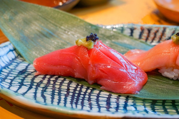 Feche acima do sushi do akami (atum rabilho) servido à mão com wasabi em conserva. Refeição de luxo japonesa.