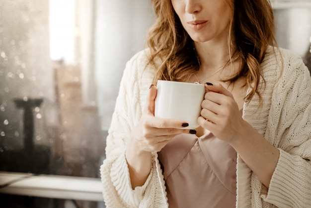 Feche acima do tiro da jovem mulher atraente, segurando a xícara de café quente