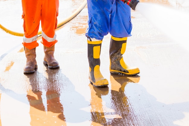 Feche acima dos boos de segurança. o trabalhador usa uma bota para limpeza de segurança pela água