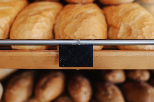 Foto feche acima dos nacos de pão deliciosos frescos na fileira nas prateleiras prontas para a venda. interior da padaria.