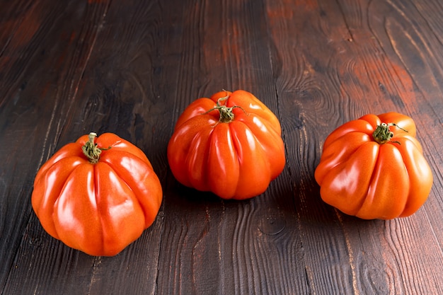 Feche acima dos tomates maduros vermelhos em uma placa de madeira. Vegetal engraçado e estranho. Comida feia.