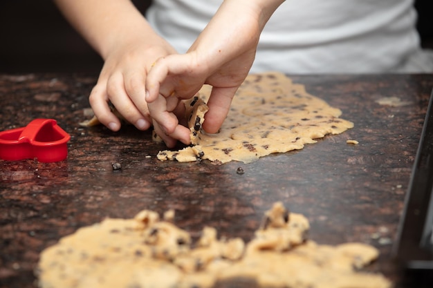 Feche as mãos da criança preparando biscoitos na cozinha