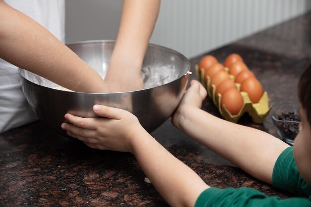 Feche as mãos da criança preparando biscoitos na cozinha