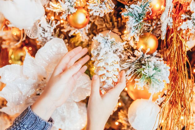 Feche as mãos da menina decorando a árvore de Natal