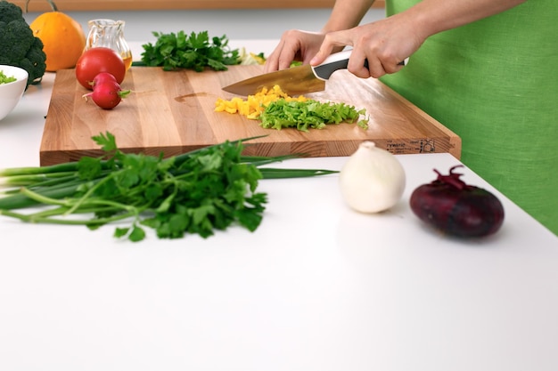 Feche as mãos da mulher cozinhando na cozinha Dona de casa cortando salada fresca Conceito de culinária vegetariana e saudável