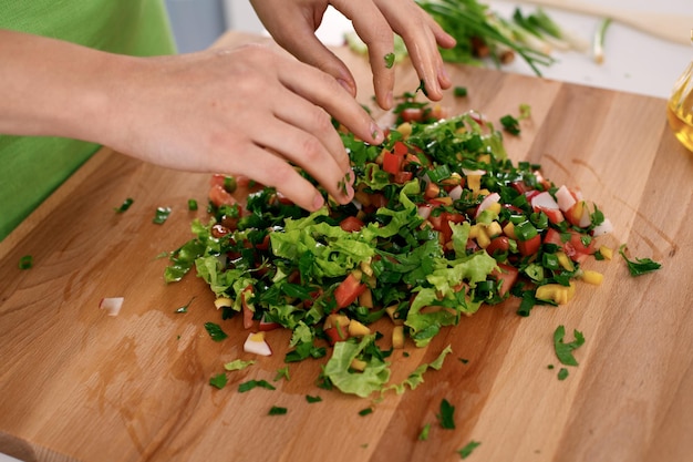 Feche as mãos da mulher cozinhando na cozinha Dona de casa cortando salada fresca Conceito de culinária vegetariana e saudável