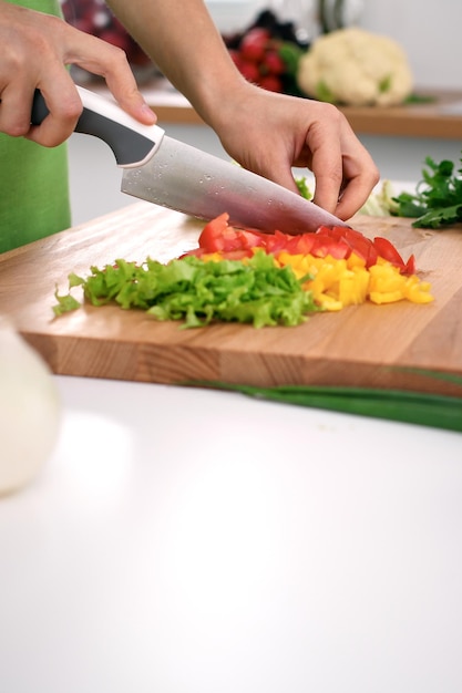 Feche as mãos da mulher cozinhando na cozinha Dona de casa cortando salada fresca