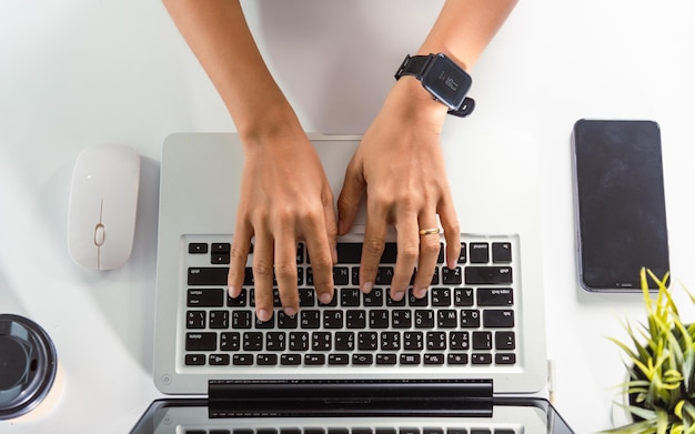 Feche as mãos da mulher de negócios sobre o teclado do laptop durante o trabalho na mesa