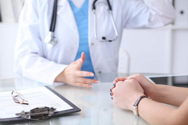 Feche as mãos de um médico e paciente discutindo algo enquanto está sentado à mesa. Conceito de medicina e cuidados de saúde