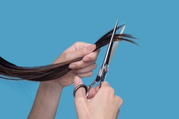 Feche as mãos de uma mulher cortando cabelo