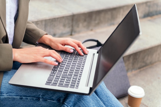 Feche as mãos de uma mulher trabalhando em seu laptop