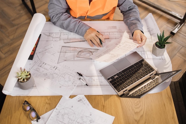 Feche as mãos do engenheiro arquiteto ou designer sentado à mesa e analisando projetos