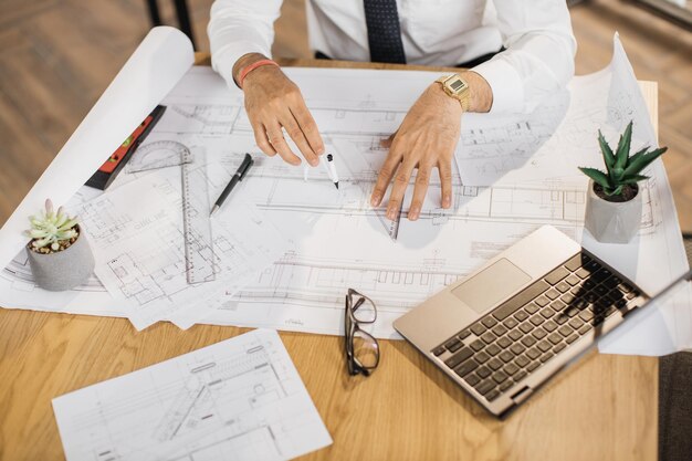 Foto feche as mãos do engenheiro arquiteto ou designer sentado à mesa e analisando projetos