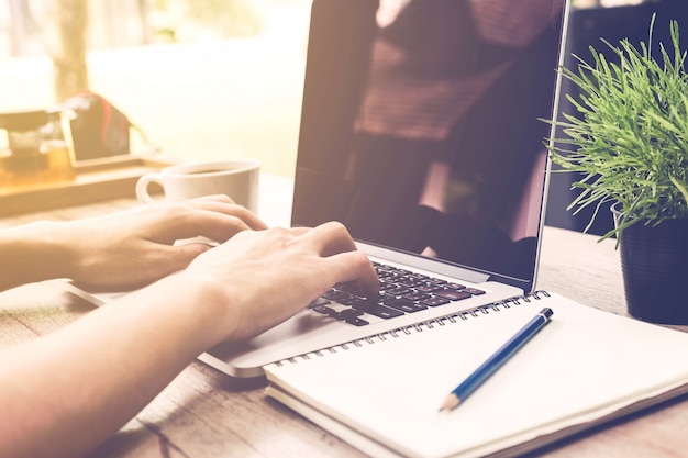 Feche as mãos do homem de negócios digitando em um laptop.