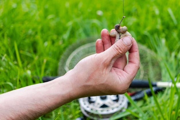 Feche as mãos dos homens colocam a isca no anzol para pescar com vara de pescar Estilo de vida recreação conceito de lazer Pescador Pegando peixe na larva do besouro