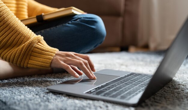 Feche as mãos femininas enquanto digita no laptop para aprendizado on-line em casa