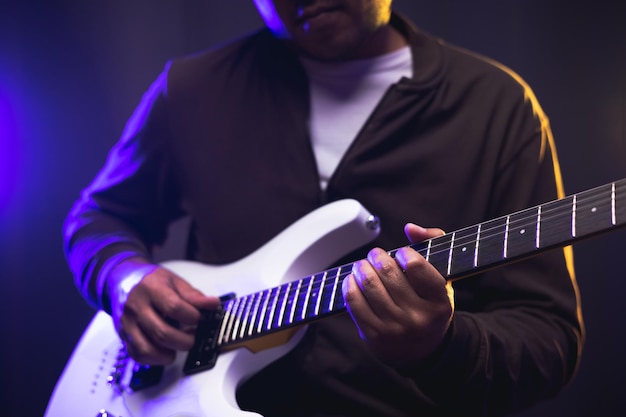 Feche as mãos jovem roqueiro tocando guitarra elétrica no palco ao vivo em concerto. com luz neon. jovem praticando heavy metal e guitarra solo no show.