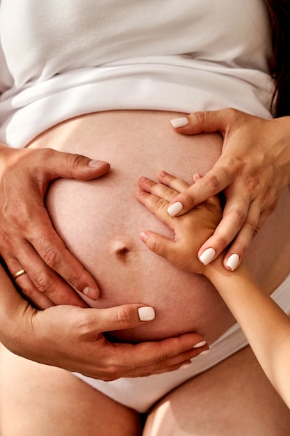 Foto feche as mãos na mãe e no pai fazendo coração na gravidez avançada de barriga grande grávida.