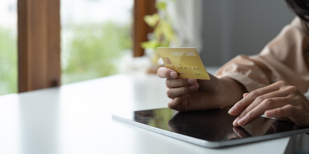 Feche as mãos segurando o cartão de crédito e usando o tablet digital compras online