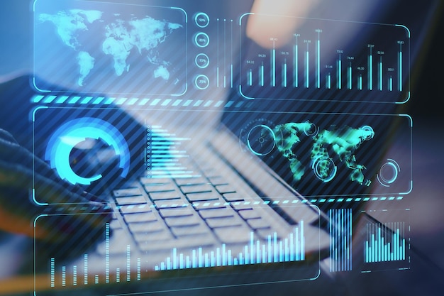 Feche as mãos usando laptop na área de trabalho com gráfico de negócios azul brilhante criativo e holograma de mapa em fundo desfocado Tecnologia finanças globais e conceito de internet Dupla exposição