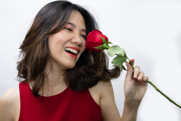 Feche as mulheres bonitas asiáticas estão cheirando a rosa vermelha e sorrindo e rindo de felicidade. um dia dos namorados e amor