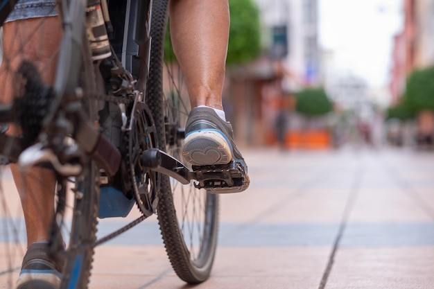 Feche as pernas da mulher casual enquanto corre sua bicicleta elétrica na rua urbana