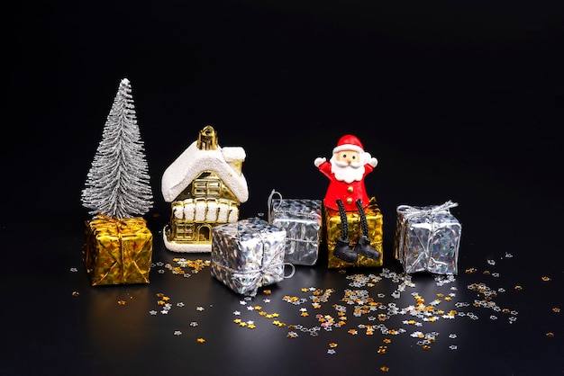 Feche bonecos de papai noel e adereços de natal em um fundo preto