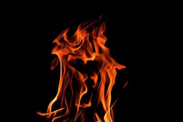 Feche chamas ardentes em fundo preto para design gráfico ou papel de parede Energia térmica vermelha e amarela acendendo combustível durante a noite Fogo em forma abstrata usado para cozinhar