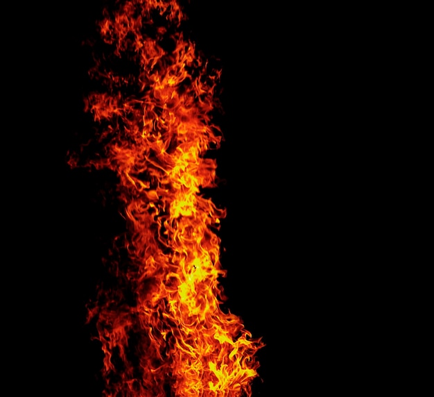 Feche chamas ardentes em fundo preto para design gráfico ou papel de parede Energia térmica vermelha e amarela acendendo combustível durante a noite Fogo em forma abstrata usado para cozinhar