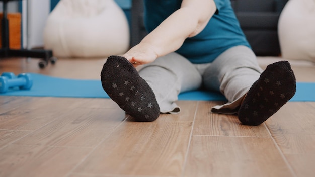 Feche de adultos mais velhos esticando braços e pernas no tapete de ioga, fazendo atividade física. pensionista se preparando para fazer exercícios físicos em casa com equipamentos esportivos. pessoa fazendo exercícios aeróbicos