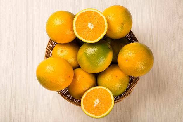 Feche de algumas laranjas em uma cesta sobre uma superfície de madeira. Fruta fresca.