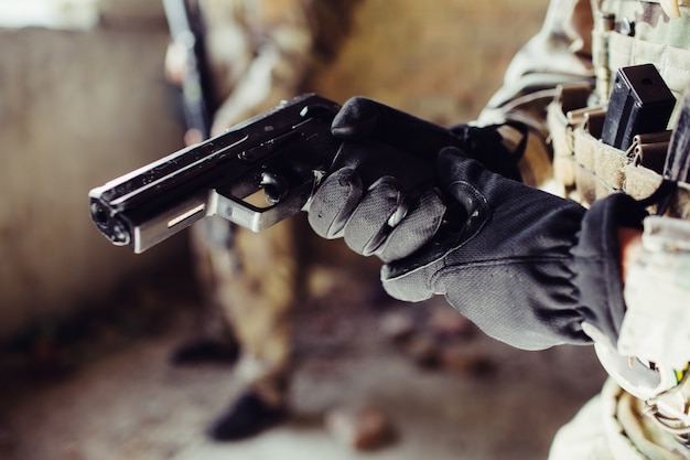 Foto feche de arma preta que soldado está segurando.