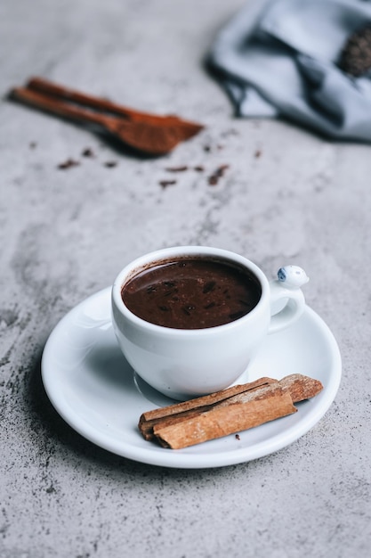 Feche de bebida de chocolate quente e canela em fundo cinza.